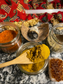 3 spice blends -- one that is green, one that is a rustic red color, and one that is yellow-orange. there is a wooden spoon scooping out the herbal spice blends.