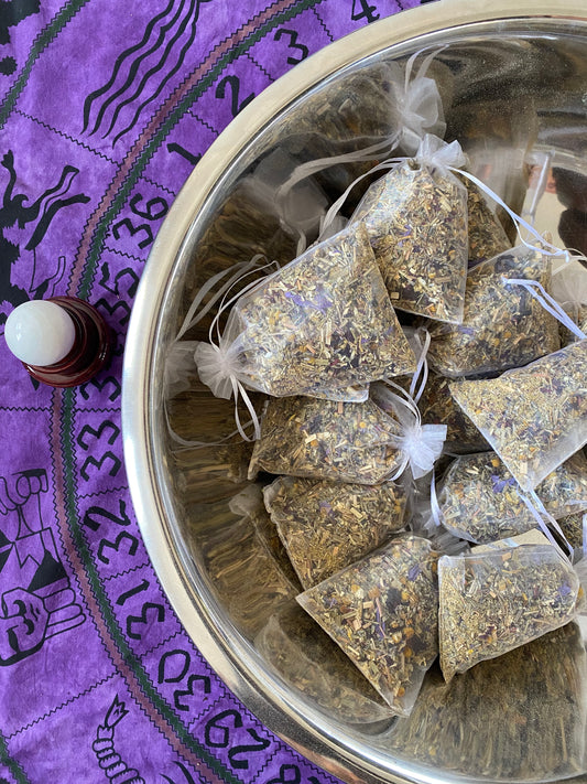 a natural, hand-made loose leaf herbal tea blend held in a beautiful sachet. these blends are potent and the colors of the herbs are purple, green, and yellow.